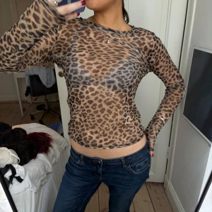 Leopardmönstrad meshtröja - Säljer en tight, långärmad meshtröja med leopardmönster. Tröjan är tunn och genomskinlig, perfekt för att skapa en cool och trendig look. 