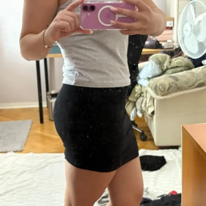 Svart tight minikjol - Säljer en svart tight minikjol med enkel design. Kjolen är kort och sitter figurnära, perfekt för dig som gillar en stilren look. Materialet känns stretchigt och bekvämt. Passar till många olika outfits.