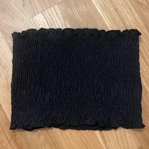 Svart tubtopp från SOC - Säljer en svart, smockad tubtopp från SOC i storlek XS/S. Toppen är elastisk och sitter tight runt kroppen, perfekt för sommaren på stranden!