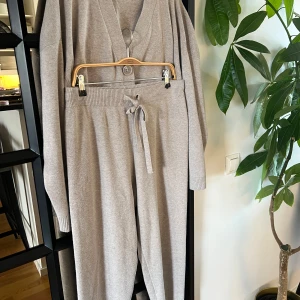 Grå mjukisbyxor från H&M med knytband - Mysiga grå mjukisbyxor från H&M med bred resår i midjan och knytband framtill. Byxorna är raka i modellen och tillverkade i ett mjukt stickat material som känns skönt mot huden. Perfekta för en avslappnad stil.