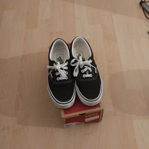 Svarta Vans sneakers med vit sula - Klassiska svarta Vans sneakers med vit sula och vita snören. Låg modell med rund tå och tydliga vita sömmar. Perfekta för en avslappnad stil och passar till det mesta. Säljes med originalkartong. Och är alldrig använda seljer dessa efter dom att jag vill byta dom mot ett par rock skor köpte dom för 700kr