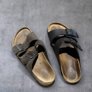 Svarta och bruna sandaler Birkenstocks  - Säljer ett par Birkenstocks på grund av att jag tappat bort en av sandalerna per färg därför säljer jag en sko i brun och en i svart. Pris kan diskuteras 