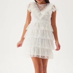 Vit spetsklänning med volanger - Superfin vit kortklänning i spets med flera lager volanger och v-ringad detalj upptill. Säljer för 599 och kostar 900 som ny och bara använt den en gång. Den är slut i storleken xs på hemsidan.