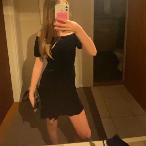 Svart offshoulder klänning - Säljer en svart offshoulder klänning med kort längd och lätt utsvängd kjol. Klänningen har en enkel och stilren design som passar perfekt till olika tillfällen. Materialet känns mjukt och följsamt mot kroppen.