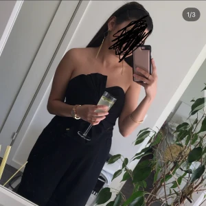 Svart body dress - Säljer en svart body/ dress med som kan bärs med eller utan axelband. Den har en väldigt snygg style på bröstet. Dressen har en elegant och stilren design som passar perfekt till fest eller fin middag. 