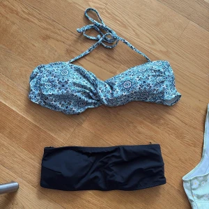 Mix av bikini toppar - Fyra olika överdelar. En blåvit mönstrad bandeau-bikini med knyt, en svart bandau bikiniöverdel, en ljusgrön topp med blommor och en mörk blå one shoulder. 70 för en!
