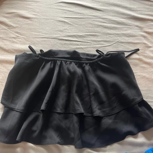 Svart volangig linnetopp från H&M - Säljer en svart linnetopp från H&M med smala axelband och dubbla volanger. Toppen har en luftig och flowy känsla, perfekt för varma dagar eller att styla lager på lager.