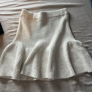 Vit stickad kjol från Lindex - Superfin vit stickad kjol från Lindex med volang nertill. Kjolen har ribbad struktur och är mjuk och stretchig i materialet. Perfekt för dig som gillar en feminin och bekväm stil. Använd bara en gång🩷
