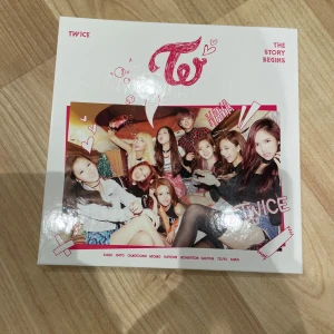 TWICE - The Story Begins (Album) - Säljer albumet 'The Story Begins' av K-popgruppen TWICE. Inkluderar CD, fotobok och 3stycken fotokort med medlemmarna. Omslaget är vitt med gruppbild och rosa detaljer. 