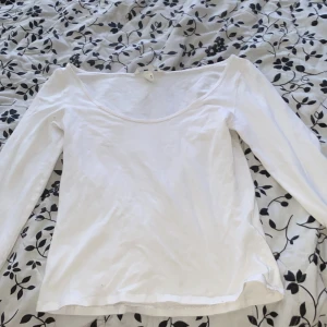 Vit långärmad topp med vid ringning - Säljer en enkel och stilren vit långärmad topp med bred, rund ringning. Perfekt att matcha med jeans eller kjol för en clean look. Mjuk och skön bomullskänsla.