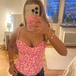 Rosa blommig body/korsett  - Säljer en söt rosa linnetopp med vitt blommönster och smala axelband. Toppen är croppad och har en figurnära passform, perfekt för varma dagar. Säljer då jag har två❤️