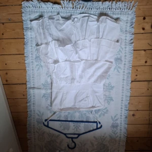 Vit volangkjol med resår i midjan - Säljer en vit kjol med flera volanger och bred resår i midjan. Kjolen är luftig och har en kort längd, perfekt för varma dagar. Enkel att matcha med olika toppar för en fräsch look.