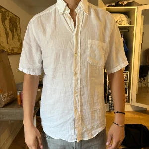 Vit linneskjorta från Eton - Säljer en fräsch vit skjorta från Eton i linnematerial. Skjortan har korta ärmar, bröstficka och klassisk krage. Passformen är slim och den stängs med knappar framtill. 