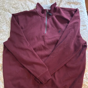 Vinröd fleece-tröja med halv dragkedja från Nautica - Vinröd långärmad fleece-tröja från Nautica med halv dragkedja och grå insida på kragen. Storlek xxl, men även fin som oversize om du bär mindre storlekar. Inga defekter. Hör av dig om du har frågor eller kom med prisförslag!!