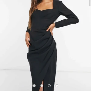 Svart långärmad klänning med drapering - Elegant svart klänning med lång ärm och snygg drapering framtill. Klänningen har en figurnära passform, markerad midja och en slits framtill. Perfekt för dig som vill ha en stilren och sofistikerad look. Storlek 34 från ASOS