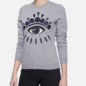 Grå sweatshirt med ögonmotiv från Kenzo - Säljer en grå sweatshirt från Kenzo med ett super fint öga broderade på bröstet.🩵🩵 Tröjan är i L men passar mig som har S/M. Inte mina bilder men kan skicka egna privat, och priset kan diskuteras 🩵