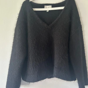 Svart fluffig tröja från H&M Edition - Mysig svart långärmad tröja från H&M Edition med v-ringning. Tröjan är fluffig och har en lite lös passform, perfekt för lager på lager. Passar dig som gillar en enkel men trendig stil. Har gjort tröjan lite kortare än vad den var från början. Den sista bilden är lånad.💓