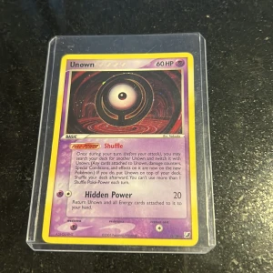 Unown - Samlarobjekt! Unown är ett unikt Pokémonkort med 60 HP och specialförmågor. Perfekt för dig som gillar Pokémon och vill utöka din samling med något annorlunda. Kortet är skyddat i plastfodral och passar både nya och erfarna samlare.