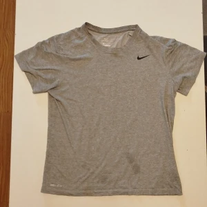 Grå tränings-tshirt från Nike - Säljer en grå Nike Dri-FIT t-shirt i storlek M. Perfekt för träning med sitt lätta och snabbtorkande material. Klassisk design med liten svart Nike-logga på bröstet och rund halsringning.