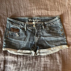 Blå lågmidjade jeansshorts  - Jättesnygga blåa och lågmidjade jeansshorts från Fishbone. De är super sköna och är i storlek L men sitter bra på mig som vanligtvis har M. Perfekta för sommaren! 