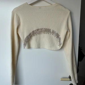 Croppad tröja  - Super snygg croppad tröja i stickat material från Zara. Den har strass baktill och har långa ärmar. Använd max 2 gånger! Har tyvärr klippt bort lappen på tröjan men tror att den är i storlek M men passar även en S.  