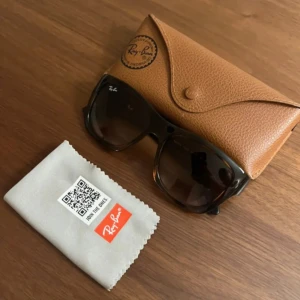 Trendiga rayband glasögon  - Snygga  solglasögon från Ray-Ban med rektangulära bågar och diskret logga på linsen. Kommer med originalfodral i brunt läder och putsduk. Perfekta för att lyfta din stil under soliga dagar.
