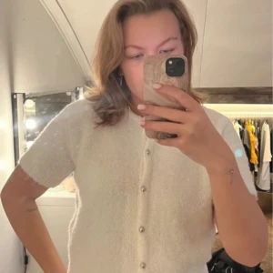 Vit kofta från Gina Tricot - Säljer en söt vit kofta från Gina Tricot i storlek M. Koftan har korta ärmar, pärlknappar framtill och är stickad i ett mjukt material 