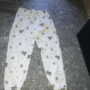 Vita mjukisbyxor med sengångarmönster - Supermysiga vita mjukisbyxor med gulligt sengångarmönster och små gröna blad. Byxorna har resår och snörning i midjan för extra komfort. Perfekta för att chilla hemma eller sova i.