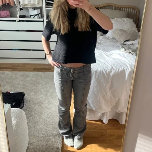 Grå bootcut jeans - Säljer ett par grå jeans med sömmar framtill och bootcut-passform. Byxorna har både framfickor och bakfickor, knapp och dragkedja i gylfen. Snygga till vardags och lätta att matcha med olika toppar. Sparsamt använda.