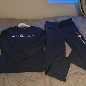 Mörkblå sweatshirt från Sail Racing - Mörkblå sweatshirt från Sail Racing med vit logga tryckt på bröstet. Tröjan har rund halsringning och långa ärmar. Tillverkad i mjukt material som passar perfekt till vardags eller träning.