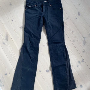 Svarta bootcut jeans från True Religion - Säljer ett par svarta bootcut jeans från True Religion med klassiska fickor och logga bak. Jeansen har låg midja och utsvängda ben, samt detaljerade bakfickor med knappar. Perfekta för dig som gillar en tidlös och cool stil. Skriv för mer frågor eller bilder, priset kan diskuteras☺️💗 köpt för 1300❣️