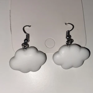 Vita molnformade örhängen INGA PLUPPAR - Supergulliga örhängen i form av vita moln. Perfekta för att ge din stil en lekfull och unik touch. Hängande modell med metallkrok.