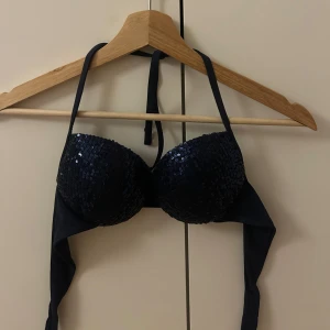 Svart Push up bikiniöverdel med paljetter - Snygg svart bikiniöverdel med glittrande paljetter. Den har knytband runt nacken och ryggen för justerbar passform. Perfekt för en dag på stranden eller vid poolen.