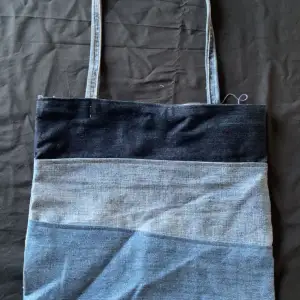 Snygg axelväska i olika nyanser av blått jeansmaterial. Väskan har en enkel design med en lång axelrem, perfekt för en avslappnad stil. Den är rymlig och praktisk för alla tillfällen 😍(hemma sydd, UF)