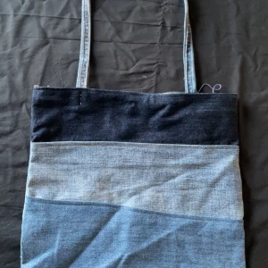 Blå axelväska i jeansmaterial - Snygg axelväska i olika nyanser av blått jeansmaterial. Väskan har en enkel design med en lång axelrem, perfekt för en avslappnad stil. Den är rymlig och praktisk för alla tillfällen 😍(hemma sydd, UF)