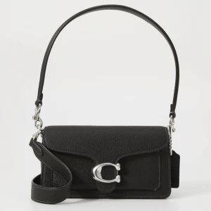 Svart axelväska med silverdetaljer - Snygg svart axelväska i skinn med stilrena silverdetaljer. Väskan har en justerbar axelrem och ett elegant spänne framtill. Perfekt för att bära dina nödvändigheter med stil. Från märket coach, nypris 4500kr, mitt pris 3500