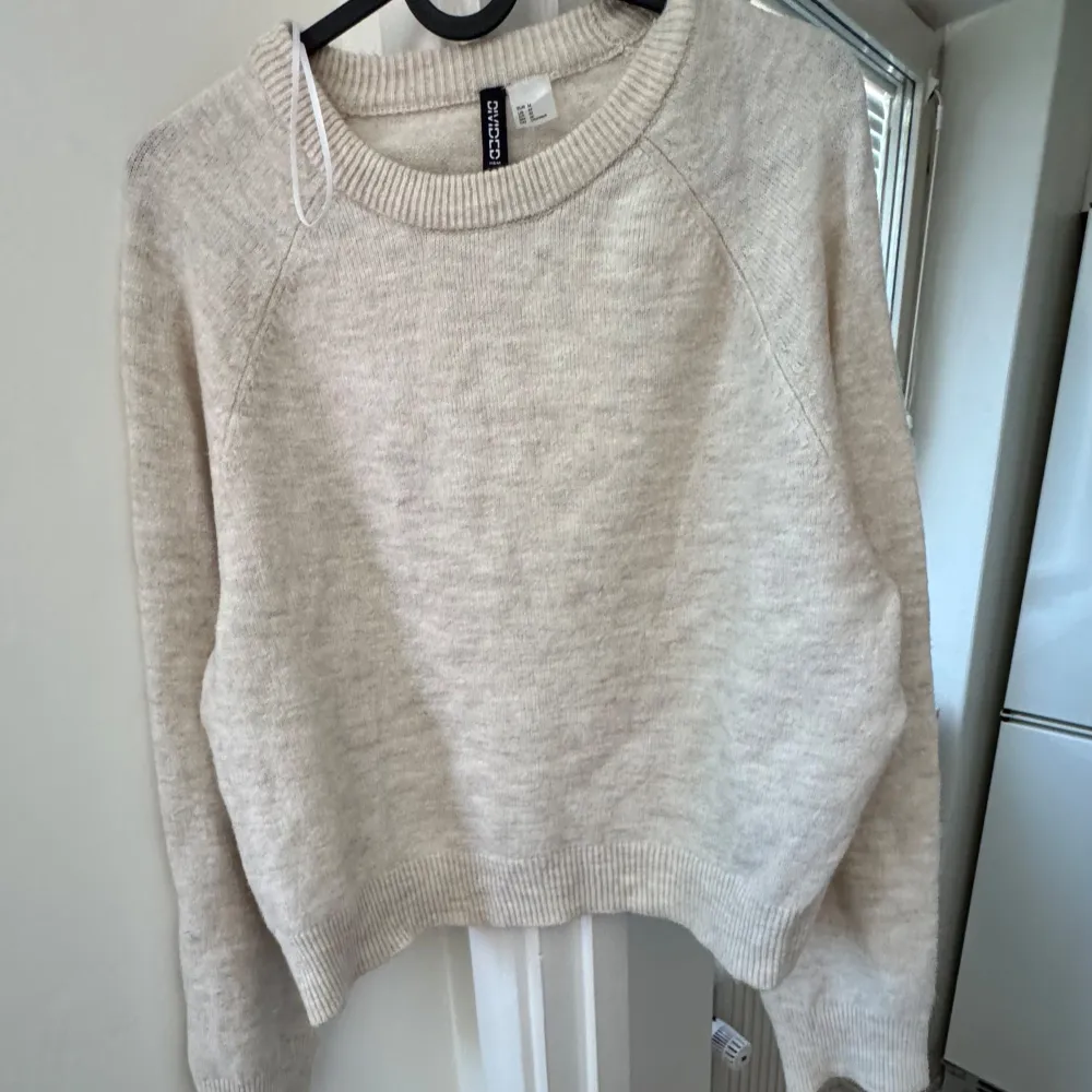 Säljer en mysig beige tröja från H&M Divided. Tröjan har en rund halsringning och långa ärmar, perfekt för kyligare dagar. Den är tillverkad i ett mjukt material som känns skönt mot huden. Passar bra till både jeans och kjol.. Neuletakit & Villapaidat.