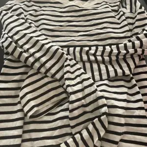 Säljer en klassisk svartvit randig långärmad tröja. Perfekt för en stilren look och passar till många olika outfits. Tröjan har en normal passform och är gjord i ett mjukt material.