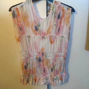 Blommig ärmlös blus - Somrig blommig blus med volangdetaljer. I strl xs. Köptes förra sommaren