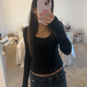 Svart ribbad tröja från Hollister - Säljer en svart ribbad tröja från Hollister i storlek XS. Tröjan har en tight passform och långa ärmar, perfekt för en stilren look. Den är tillverkad i ett mjukt material som känns skönt mot huden. Perfekt för både vardag och speciella tillfällen.