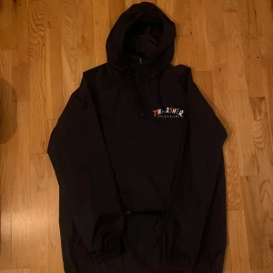 Navy blå vindjacka från Thrasher - Säljer en navy blå vindjacka från Thrasher med färgglad logga på bröstet. Jackan har en huva och dragkedja framtill. Perfekt för blåsiga dagar och en stilren look.