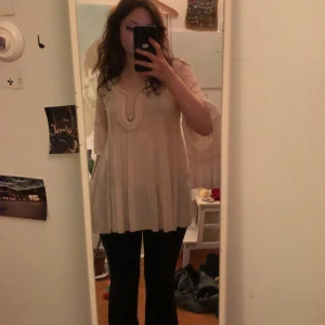 Beige blus med spetsdetaljer - Charmig beige blus med vackra spetsdetaljer och volanger. Blusen har trekvartsärmar och en lös passform, perfekt för en bohemisk look. Den har en rund halsringning med en liten öppning framtill. Har bara använt den en gång!