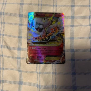 M Altaria EX Pokémonkort - Säljer ett Altaria EX Pokémonkort med holografisk yta. Kortet har en färgglad design med Altaria i fokus och texten 'Mist Purge'. Perfekt för samlare eller Pokémon-entusiaster!