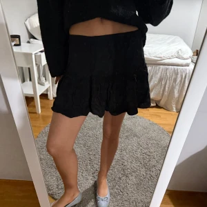 Svart kortkjol med volang - Snygg svart kortkjol med volangdetaljer. Perfekt för en stilren look. Okänt märke men den är i strl 34 och jag är ca 1.70cm🙌🏼❤️‍🔥