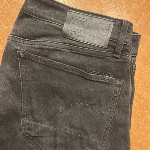 Svarta jeans från G-Star RAW - Snygga svarta jeans från G-Star RAW, modell 3301 Straight. Klassisk femficksdesign med knappgylf och logotypdetaljer. Perfekta för en stilren look.