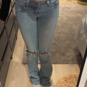 Ljusblå bootcut jeans - Lågmidjade jeans från nelly, bra skick! Har gjort egna hål. Nypris 699. 