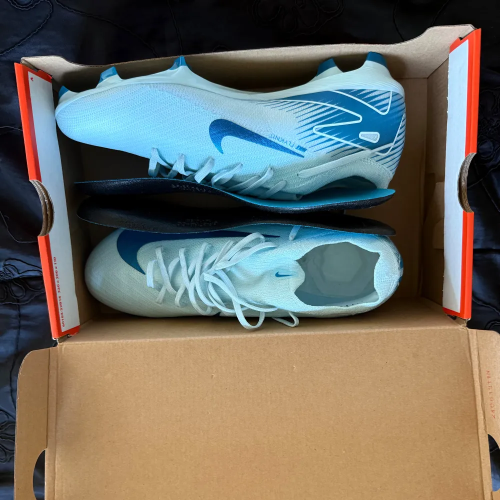 Snygga ljusblå Nike fotbollsskor med mörkblå detaljer och snörning. Perfekta för fotbollsplanen med en stilren design och bra grepp.. Kengät.