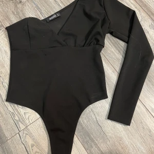 Svart långärmad bodysuit från Missguided - Snygg svart bodysuit från Missguided. Är i en medium men är mindre i storlek
