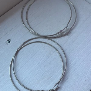 2 par örhängen - 2 par silvriga örhängen, exakt likadana bara att det ena paret är en storlek mindre (se bild 2). Väldigt fina och sitter snyggt! Bara använt det ena paret några fåtal gånger så i väldigt bra skick!