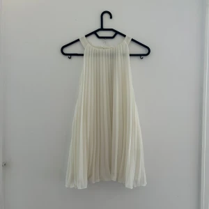 Vit plisserad topp från H&M - Superfin vit plisserad topp från H&M i storlek L. Toppen är ärmlös och har en luftig, flowy känsla. Perfekt för sommar!